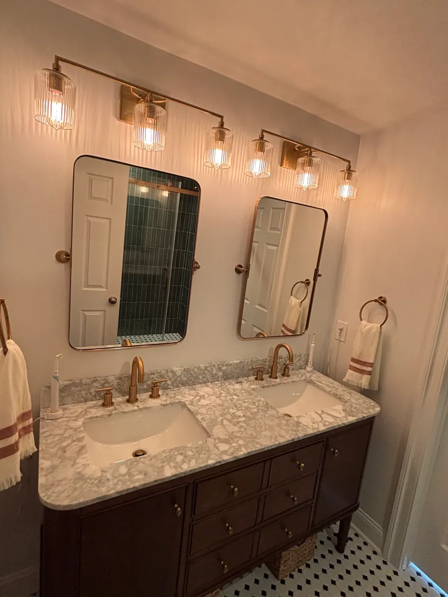Bathroom vanity with brass sconces and a framed mirror