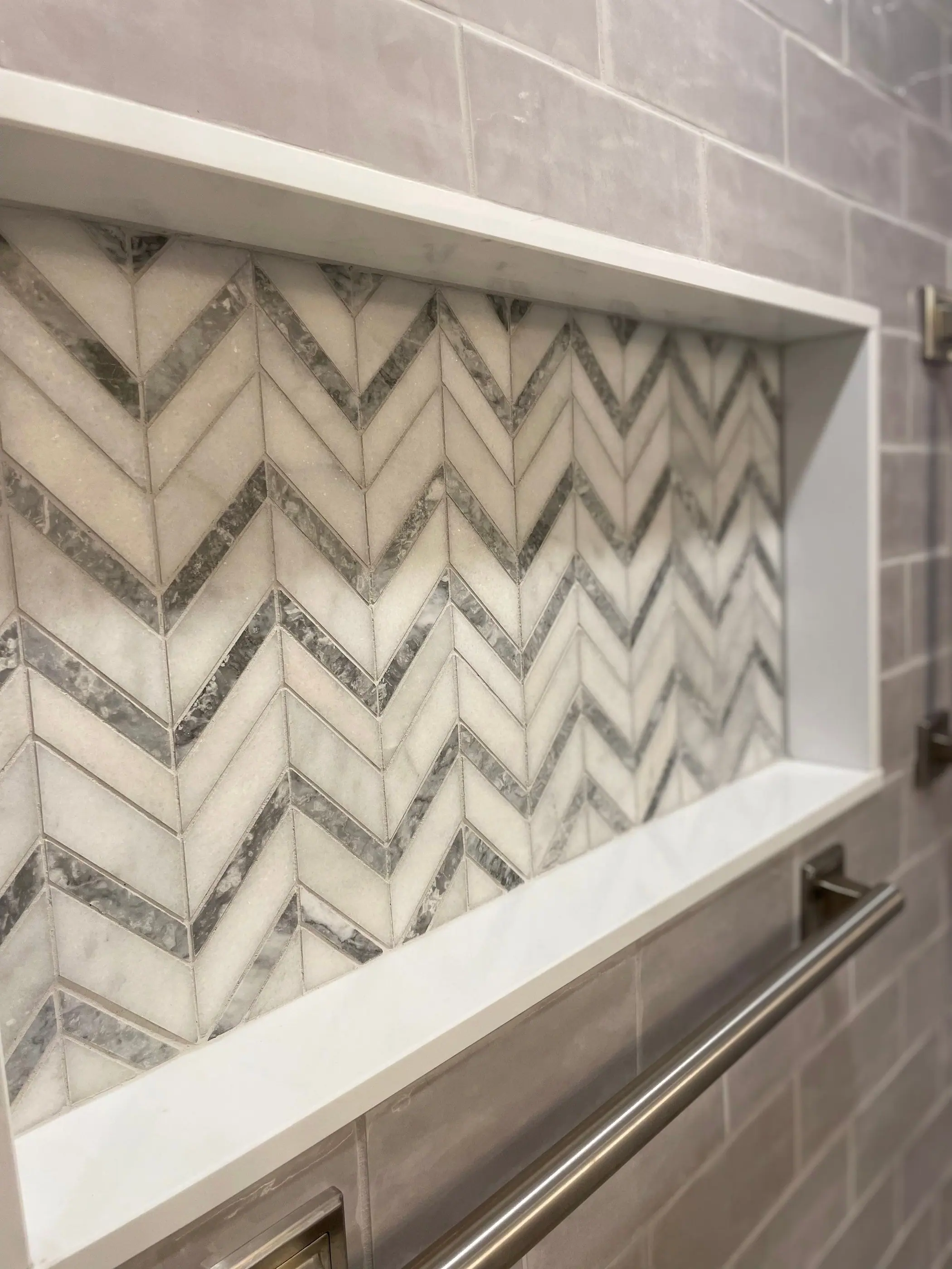 Chevron marble niche set into a tiled shower wall