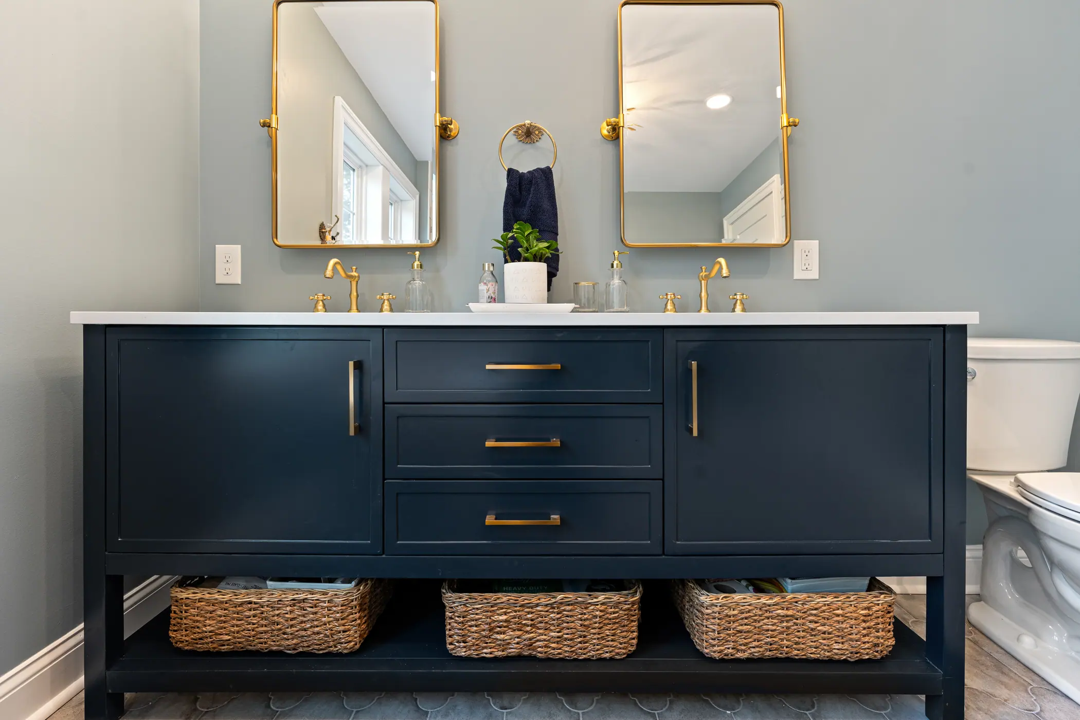 Navy double vanity with brass mirrors and sconces