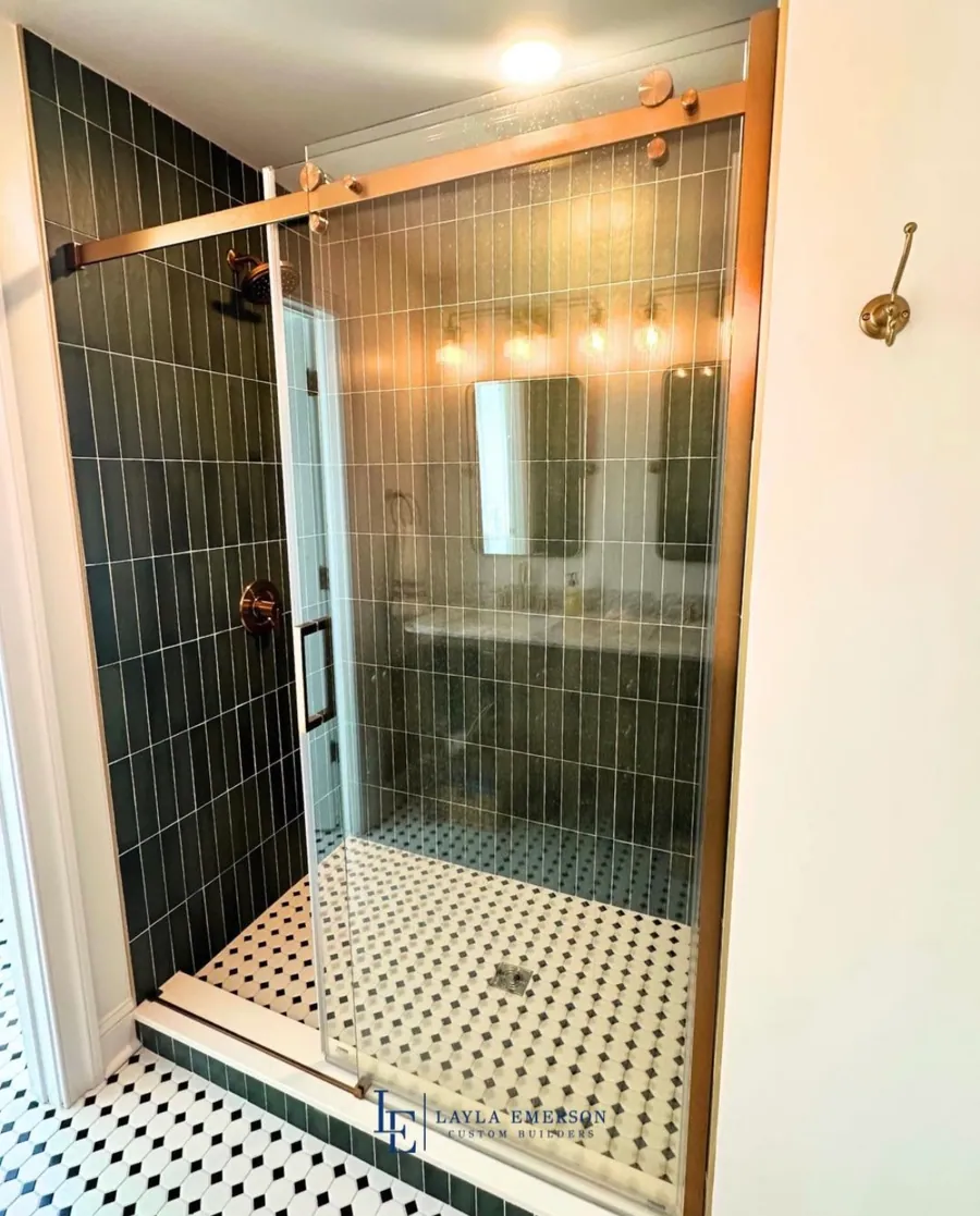 Green tiled shower with brass fittings and glass surround