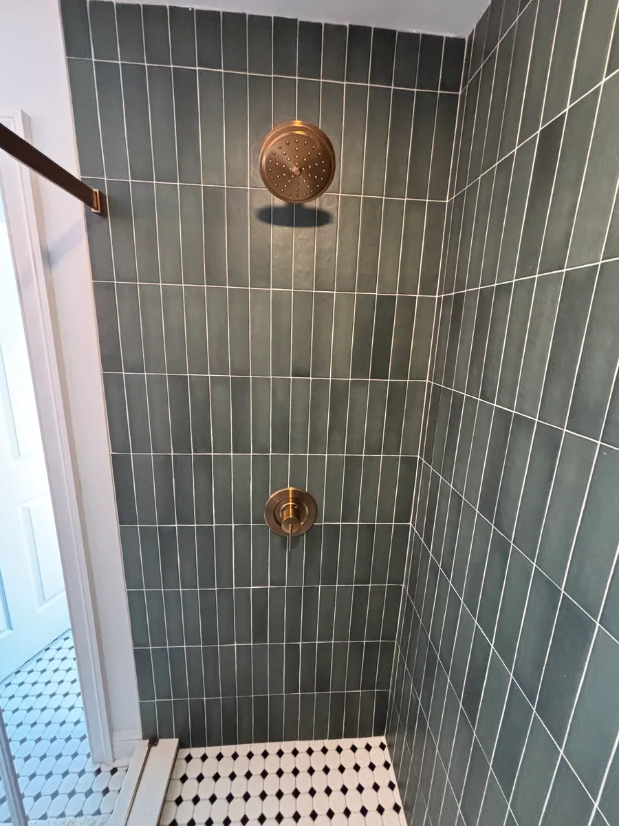 Green tile detail with a brass shower set