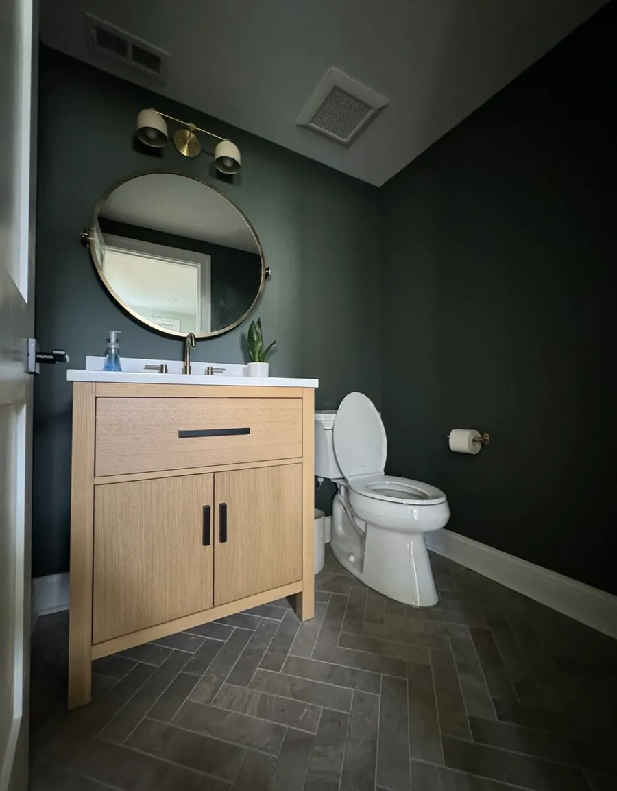 Dark green powder room with an oak vanity
