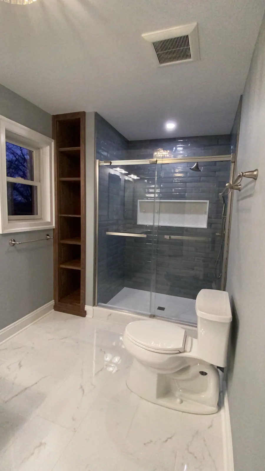 Bathroom with a grey tiled shower and glass panel