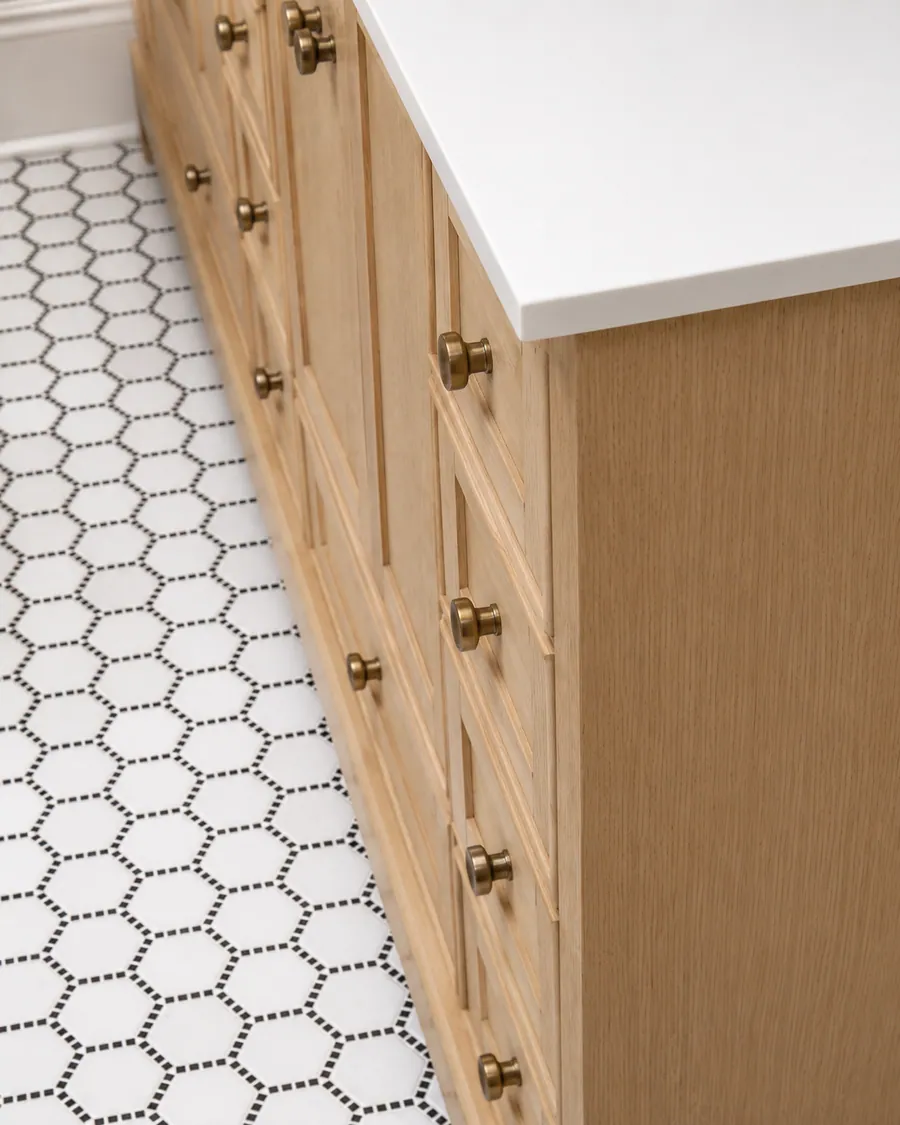 Hex tile floor with a wood vanity and round mirror