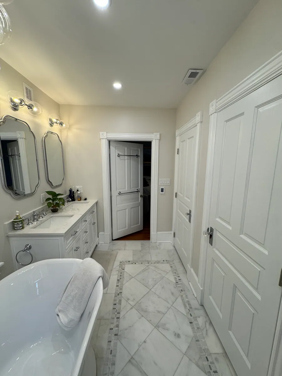 Marble primary bathroom with a tub and double vanity