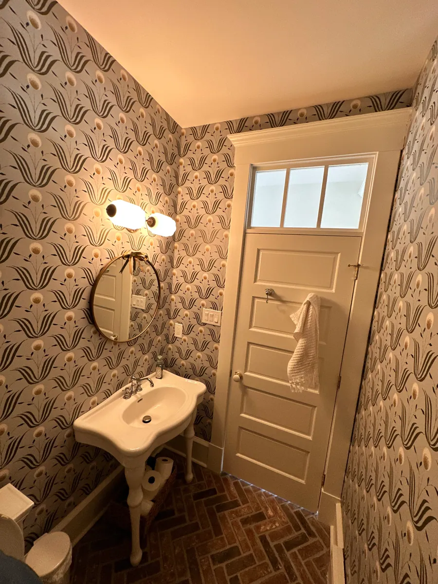 Powder room with wallpaper and a pedestal sink