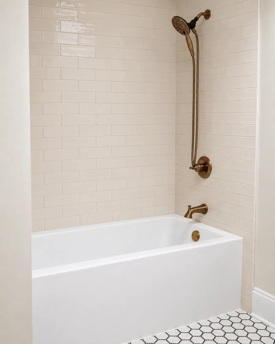 Soaking tub with a brass shower set and tiled surround
