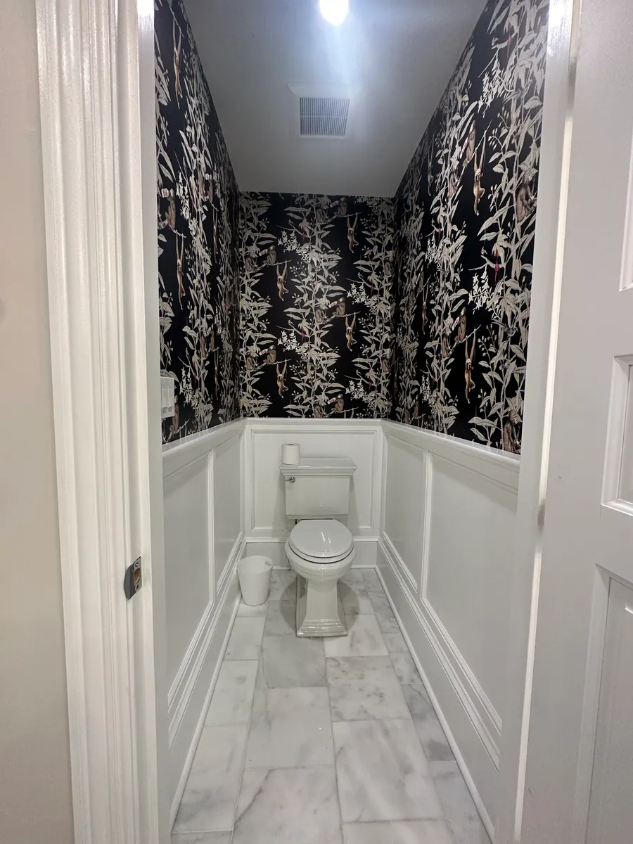 Bathroom with patterned wallpaper and a tiled tub surround