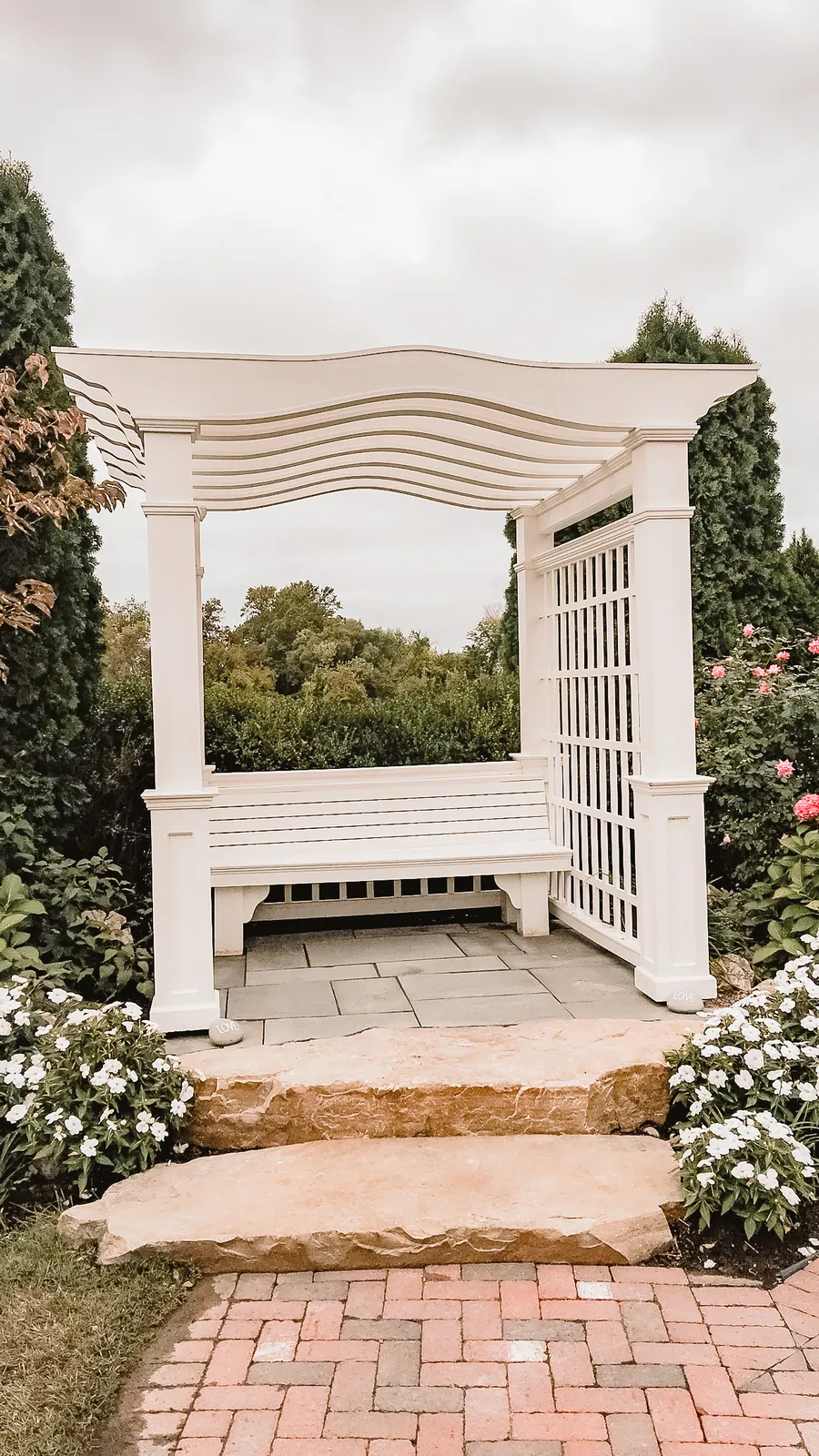 White arbor with a built in bench in a garden