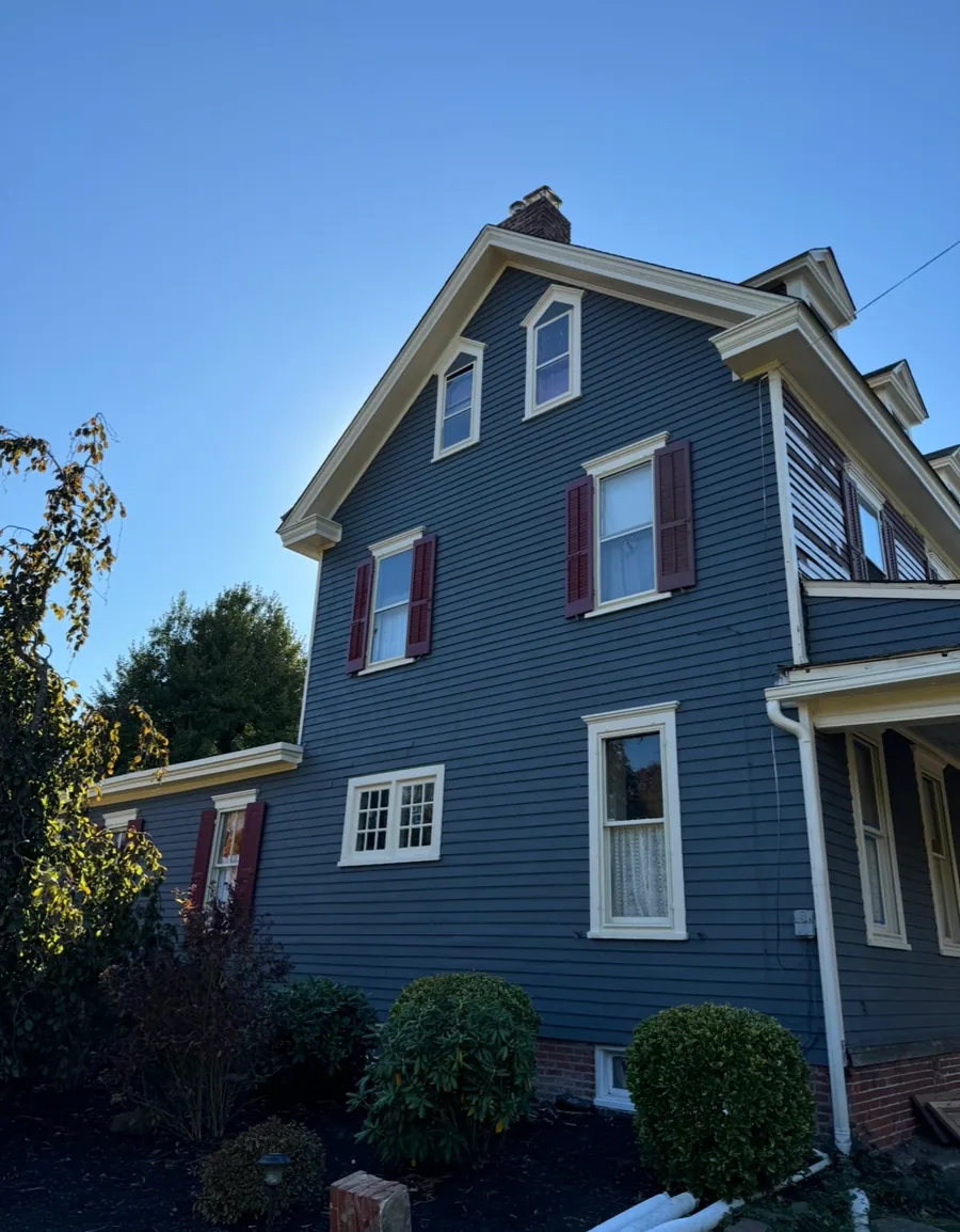 Restored historic home in blue with red shutters