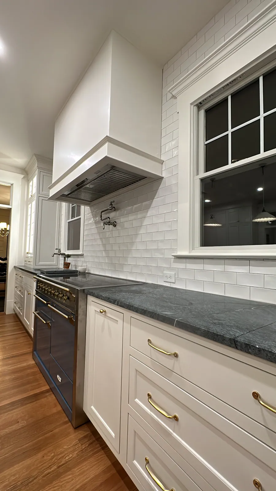 White kitchen with a black range and custom hood surround
