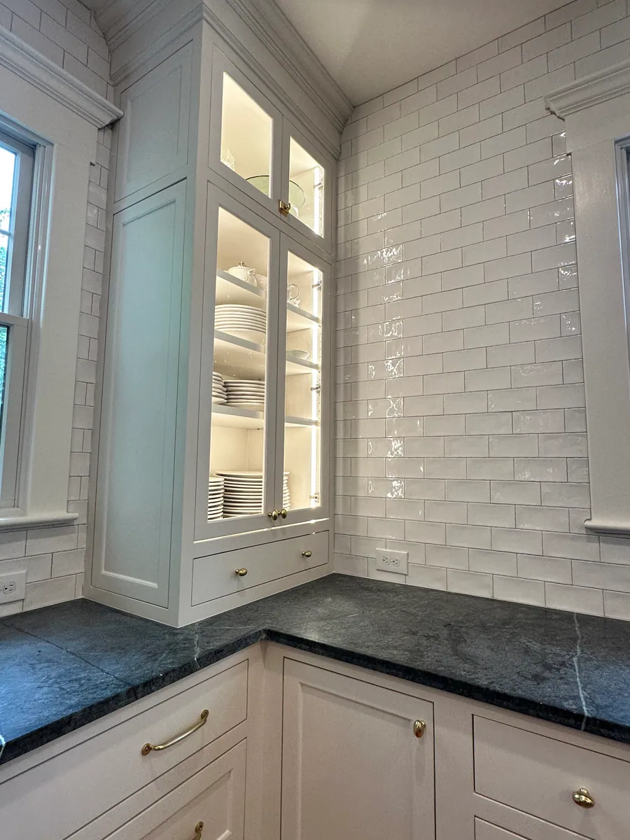 Corner glass cabinet above white subway tile