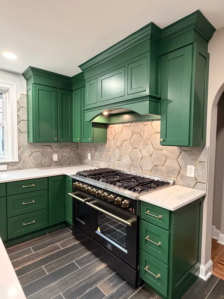 Green kitchen cabinetry with a black range and hex tile backsplash