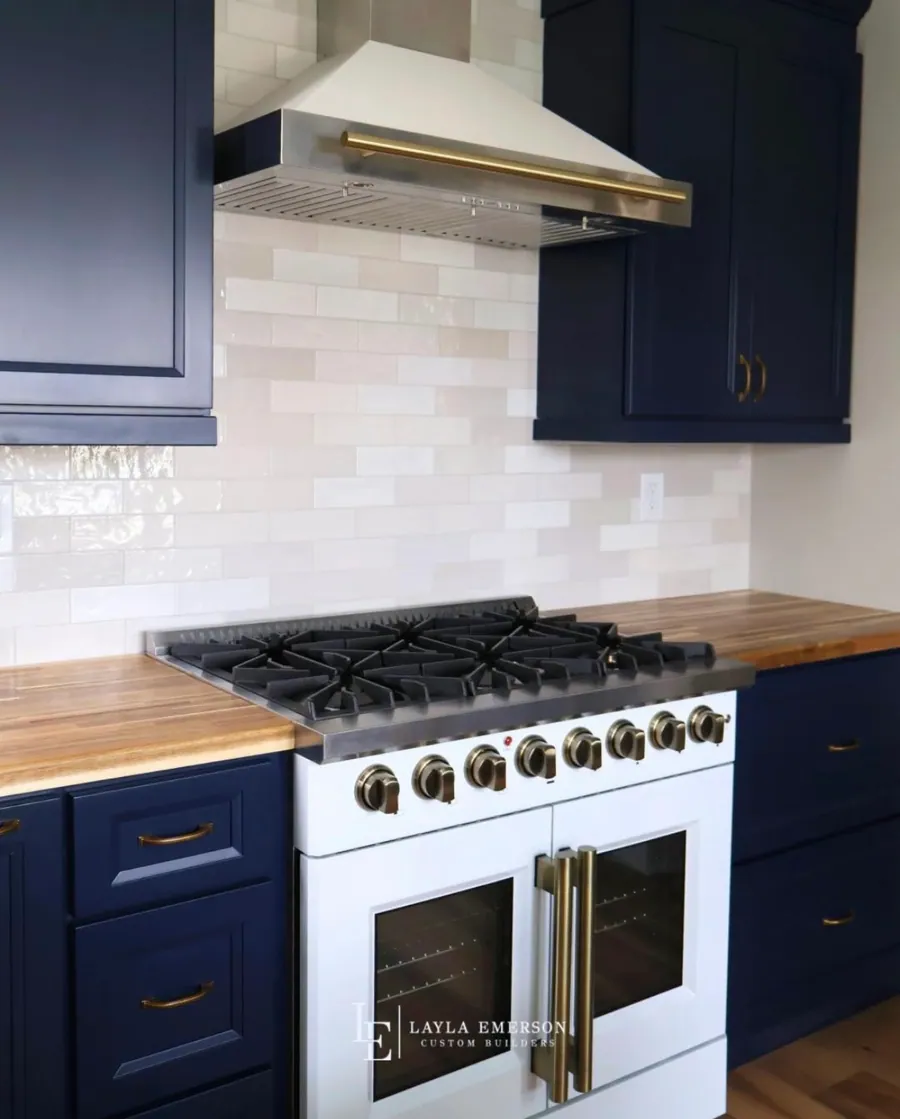 Navy kitchen with a white range and butcher block counter