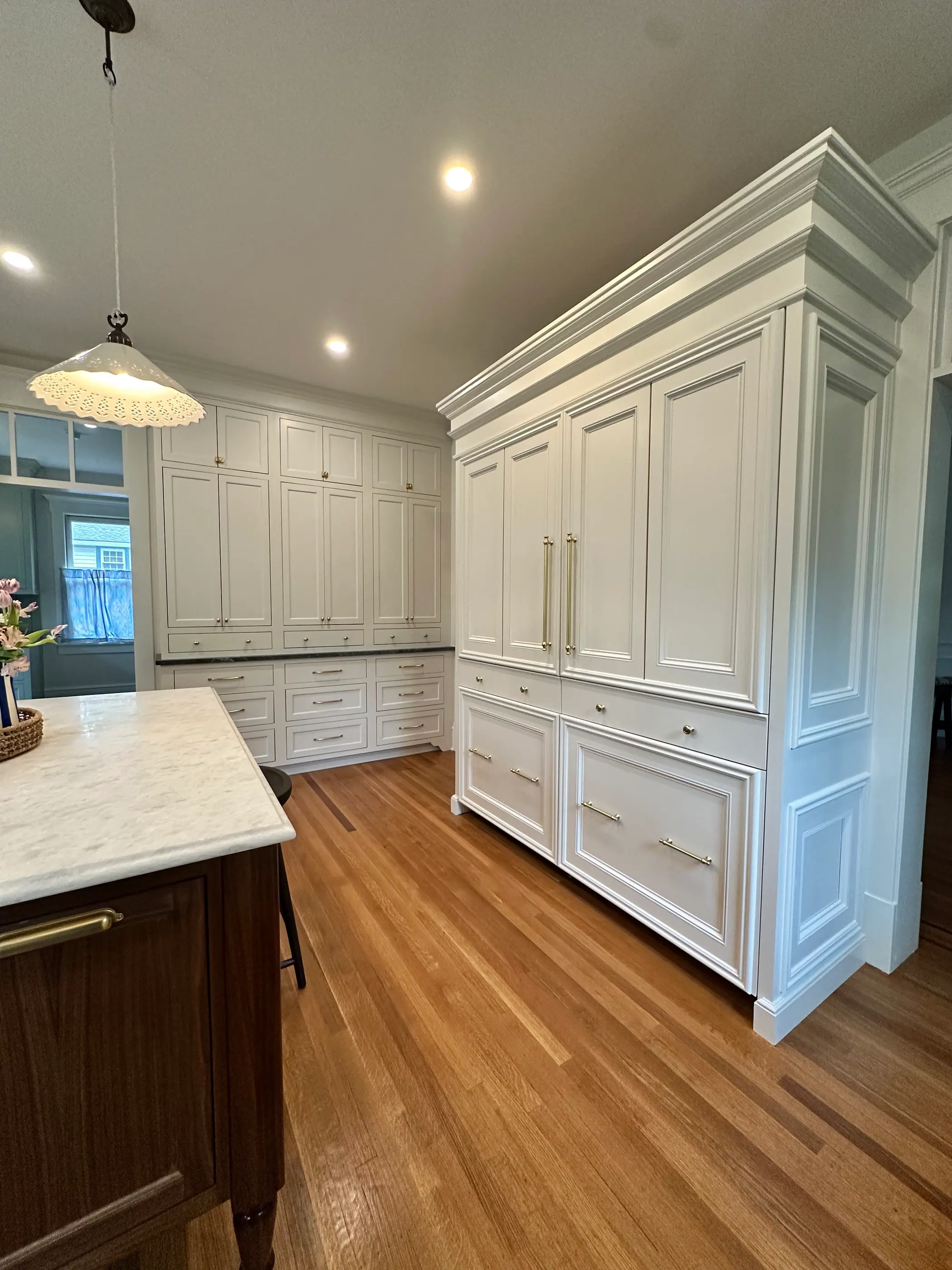 Panelled white kitchen with tall cabinetry and a marble island