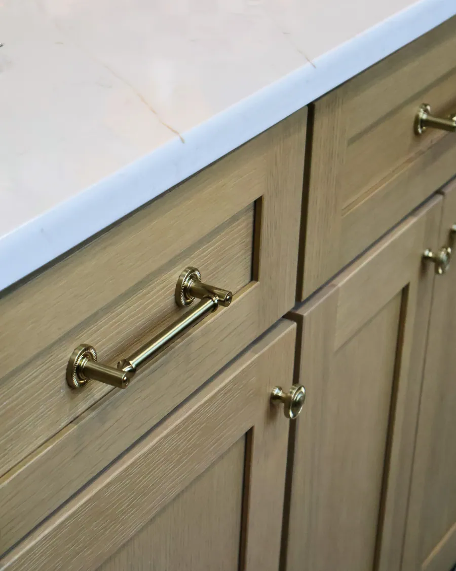 Sage green cabinet run with brass pulls and a marble counter