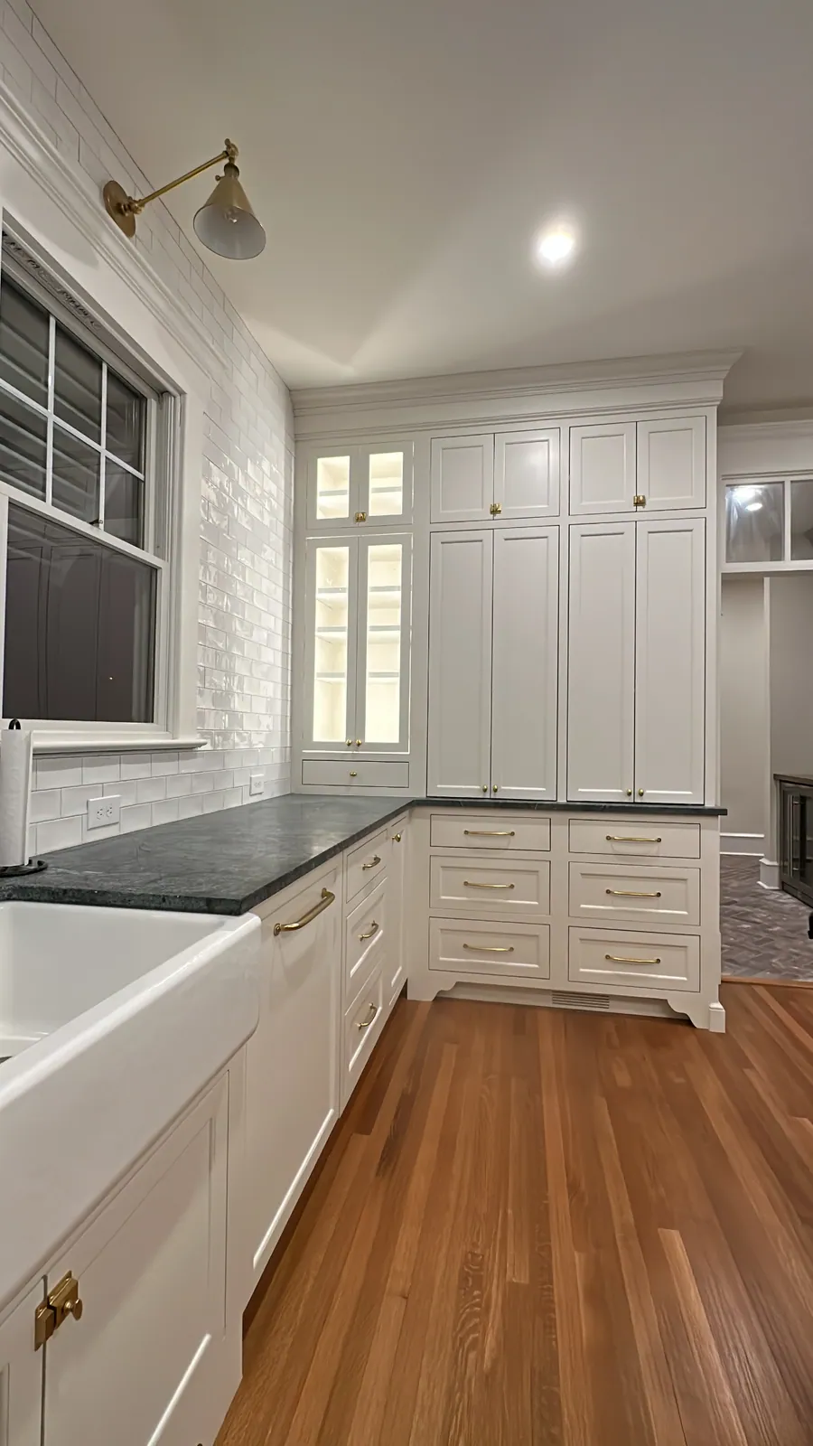 White kitchen with soapstone counters and a brass wall sconce