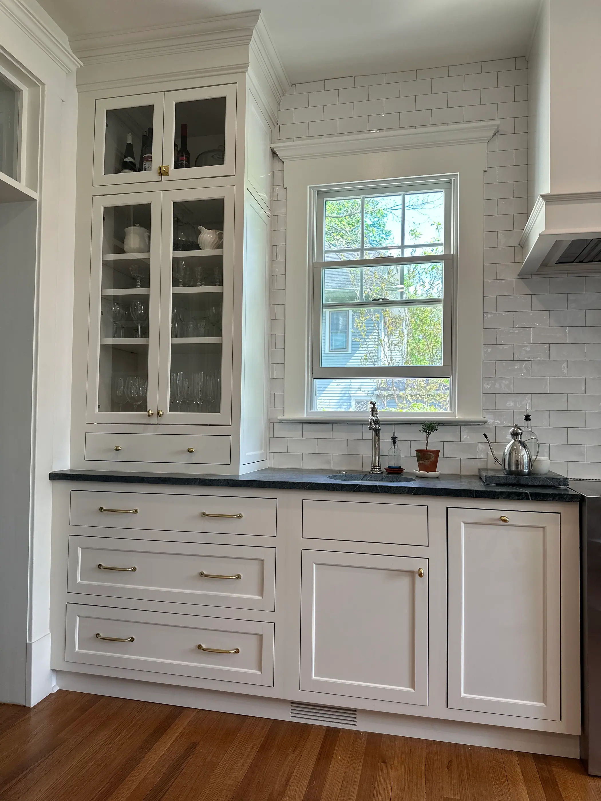White cabinetry with soapstone counters and subway tile