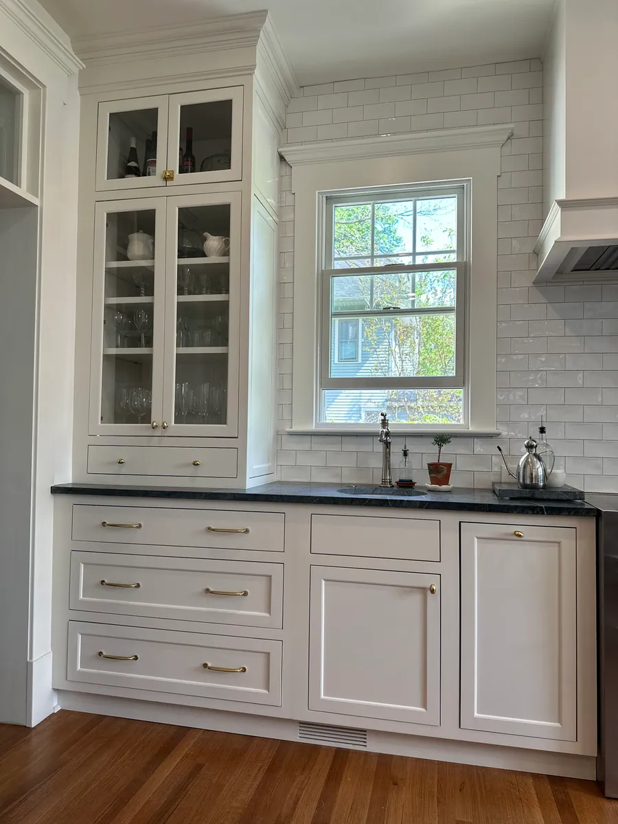 White cabinetry with soapstone counters and subway tile