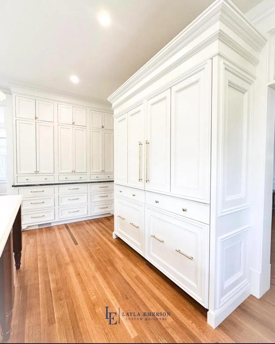 Floor to ceiling white kitchen cabinetry with brass pulls