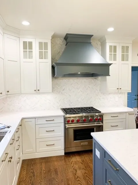 White kitchen with a custom range hood and marble counters
