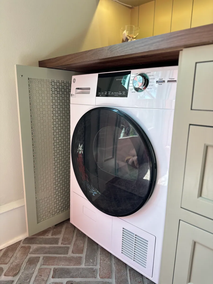 Laundry hidden behind cabinetry with mesh panel doors