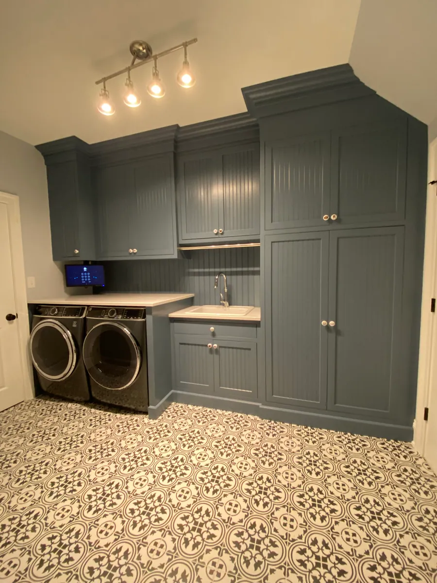 Laundry room with grey green cabinetry and patterned floor tile