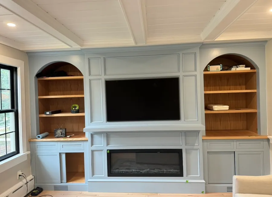 Arched built ins beside a fireplace under a coffered ceiling