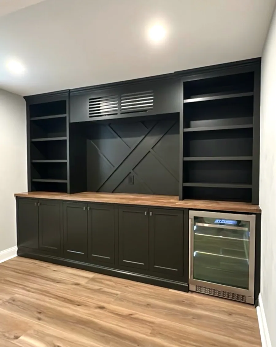 Dark green bar with a wood counter and beverage fridge
