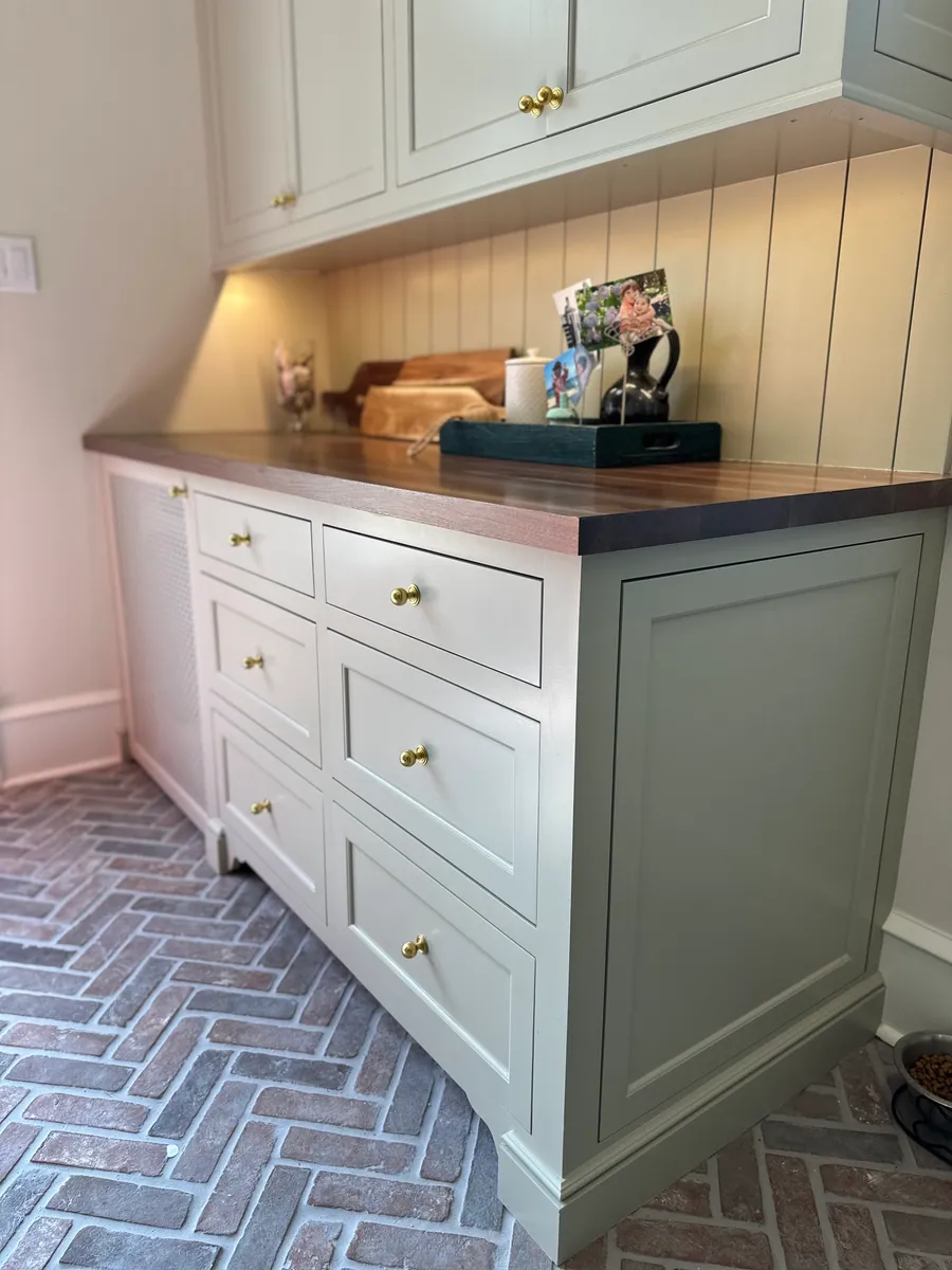 Cabinetry island with a wood top over a brick herringbone floor