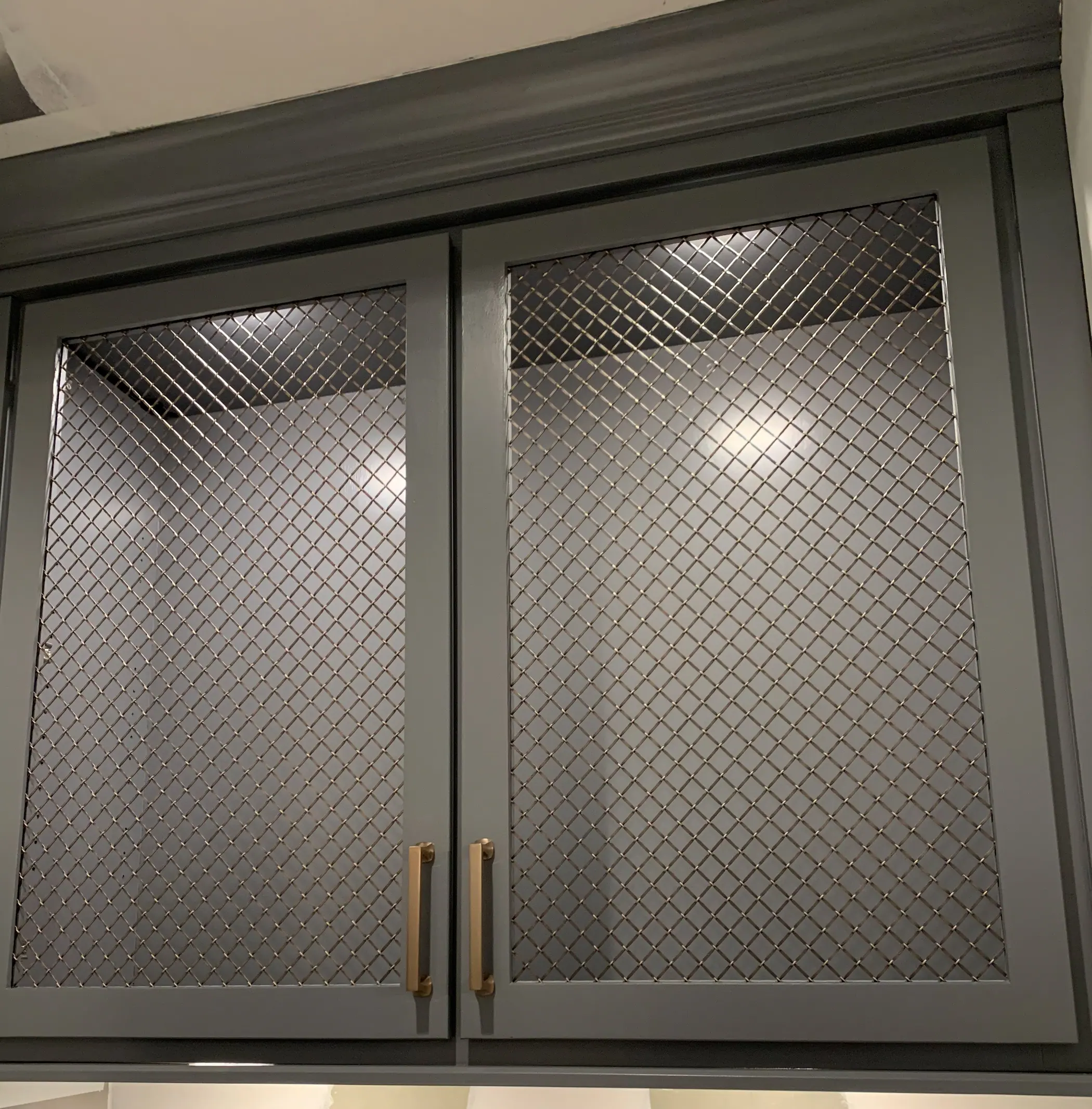 Mesh cabinet door detail with brass pulls