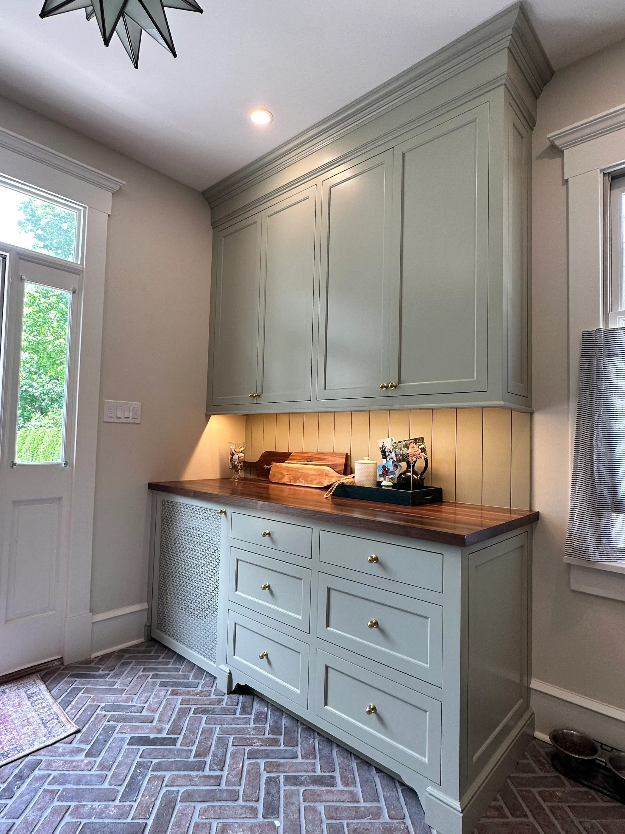 Mudroom cabinetry with a walnut top over a brick floor