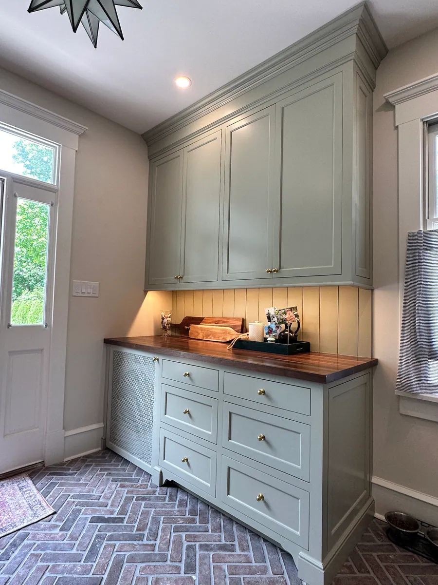 Mudroom cabinetry with a walnut top over a brick floor