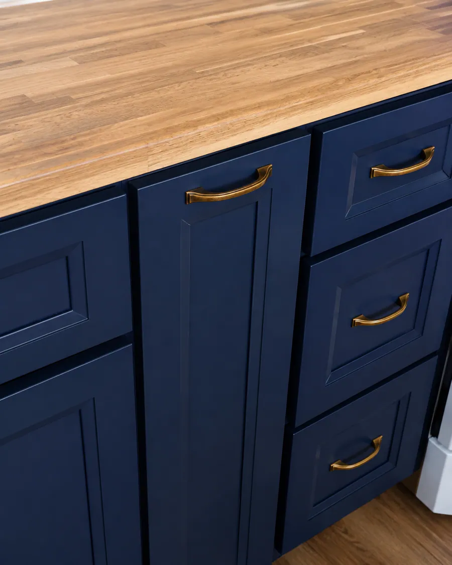 Navy cabinets with a solid wood counter and brass pulls