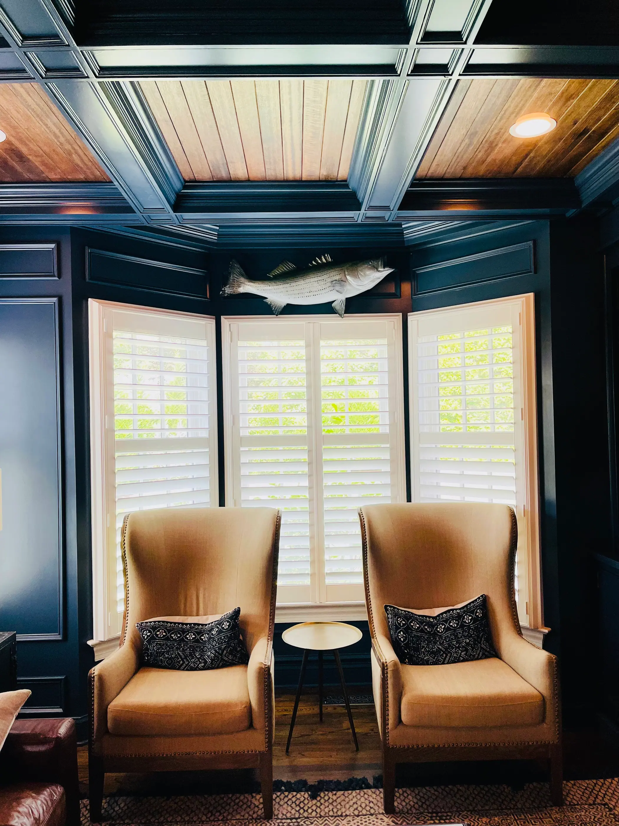 Navy sitting room with a panelled ceiling and plantation shutters
