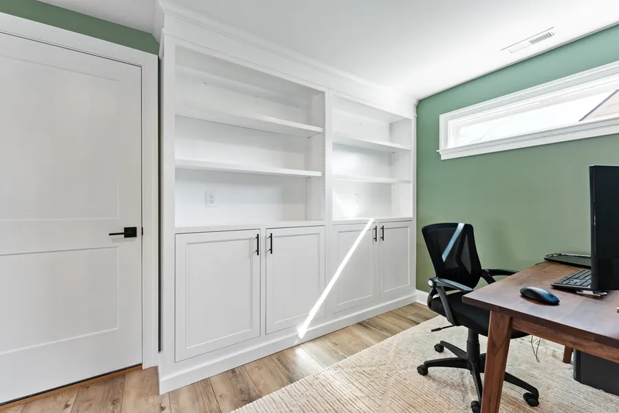 White built in office cabinetry against a green wall
