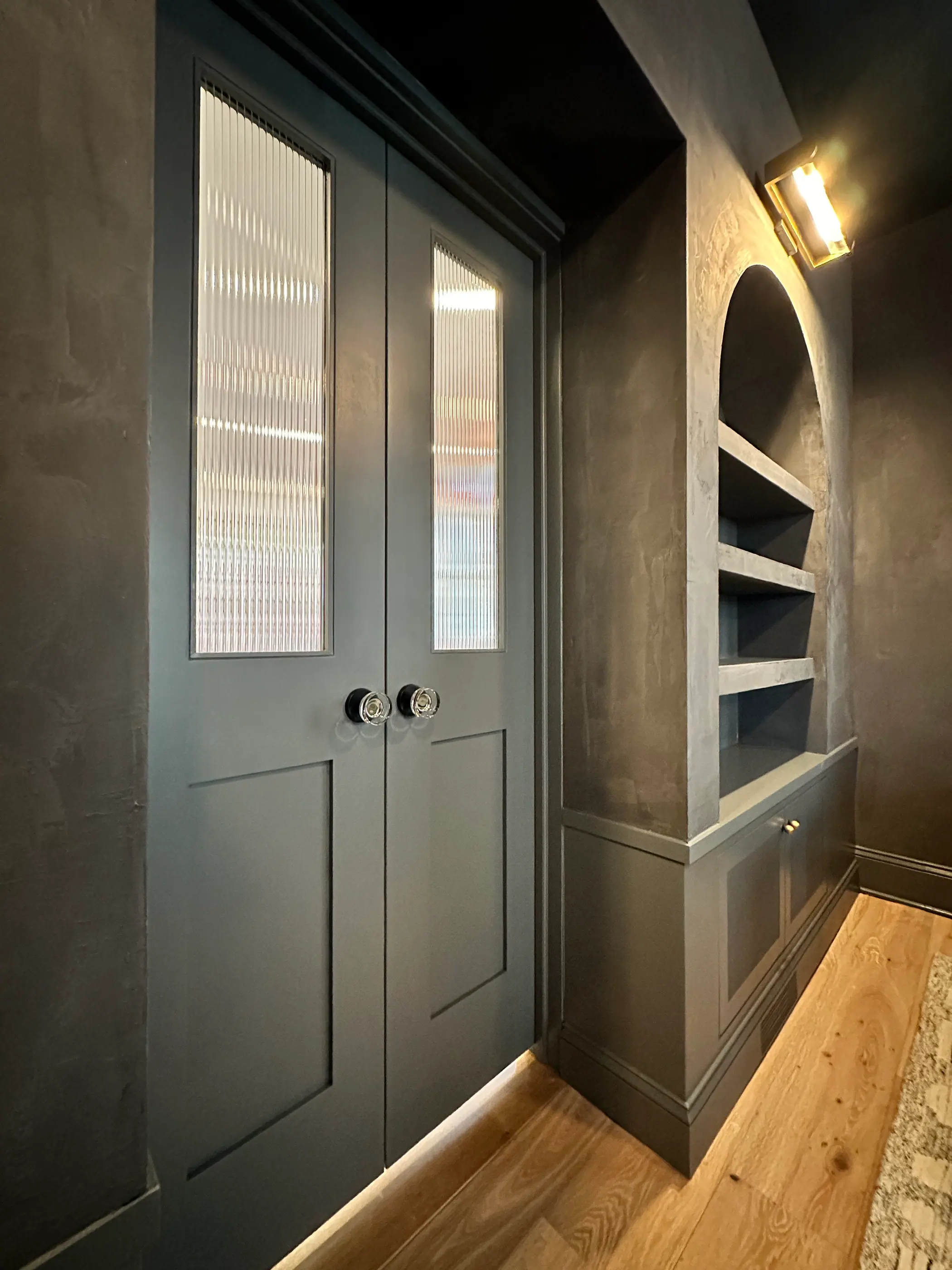 Reeded glass doors beside an arched display niche