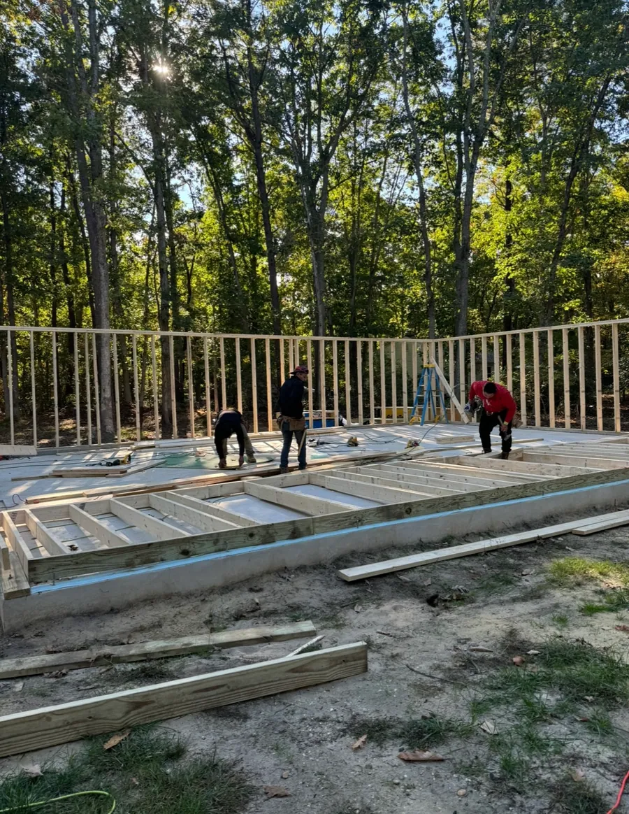 Crew raising framed walls on a slab