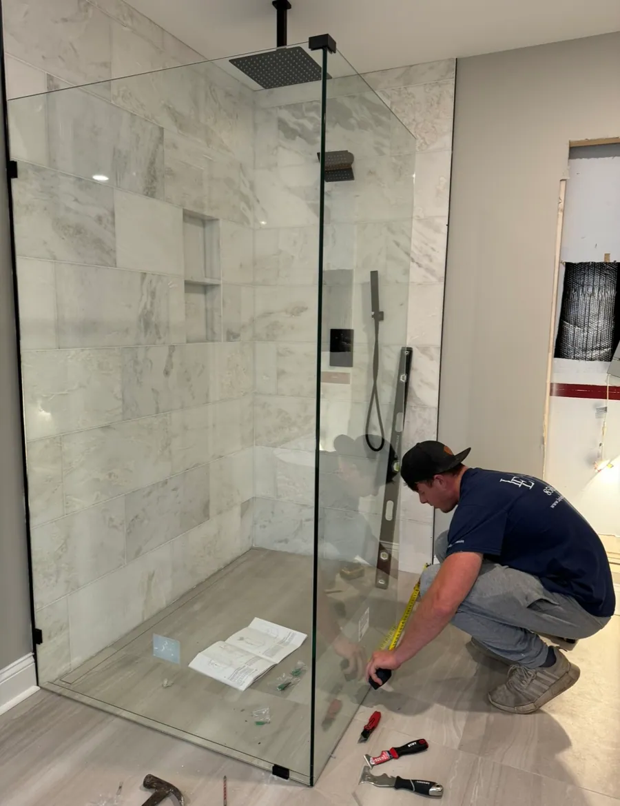 Installer fitting a frameless shower door