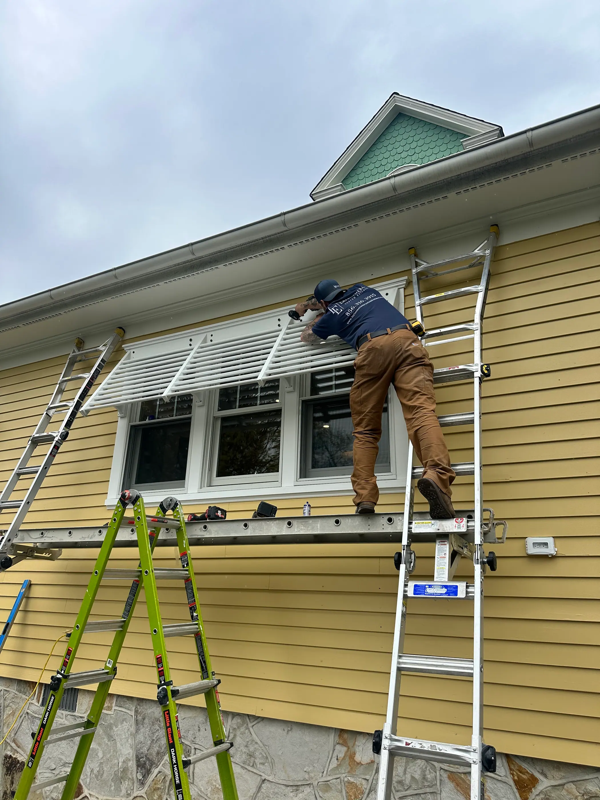 Crew working from ladders on exterior siding